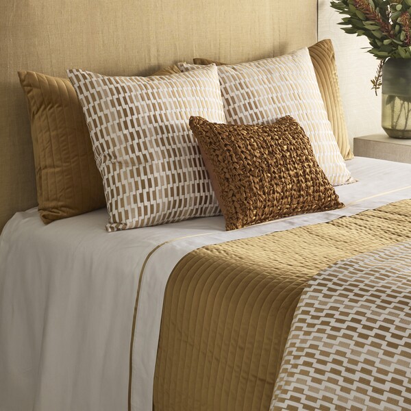 gold and white pillows on a bed